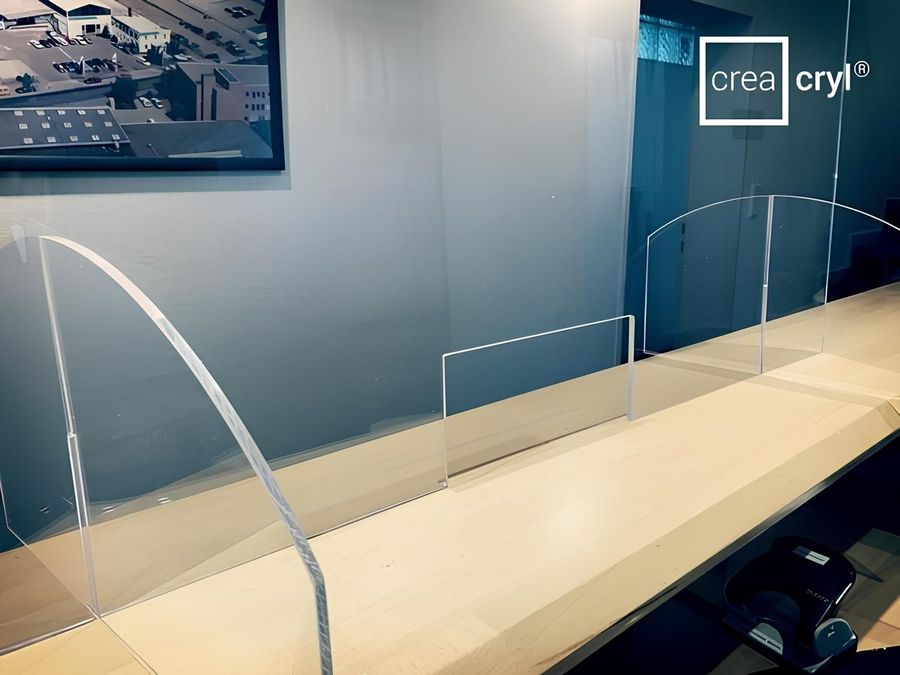 Transparente Acrylbarrieren auf einer Holztheke mit einem Logo in der Ecke.